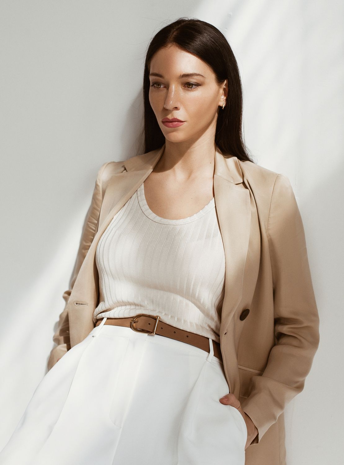 Woman in stylish tan professional outfit against white background.