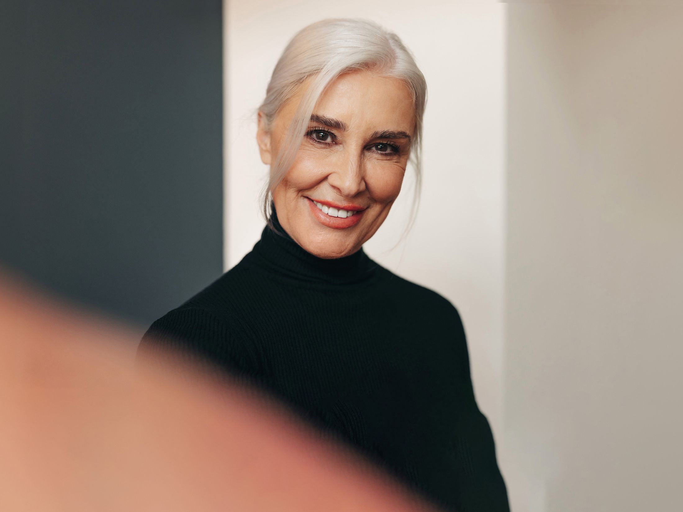 Smiling woman in black turtleneck sweater.
